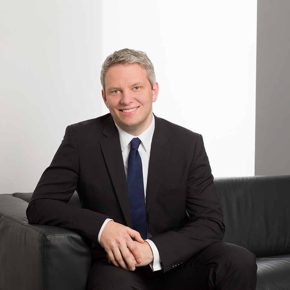 Ein Mann in Anzug und Krawatte sitzt auf einer Couch