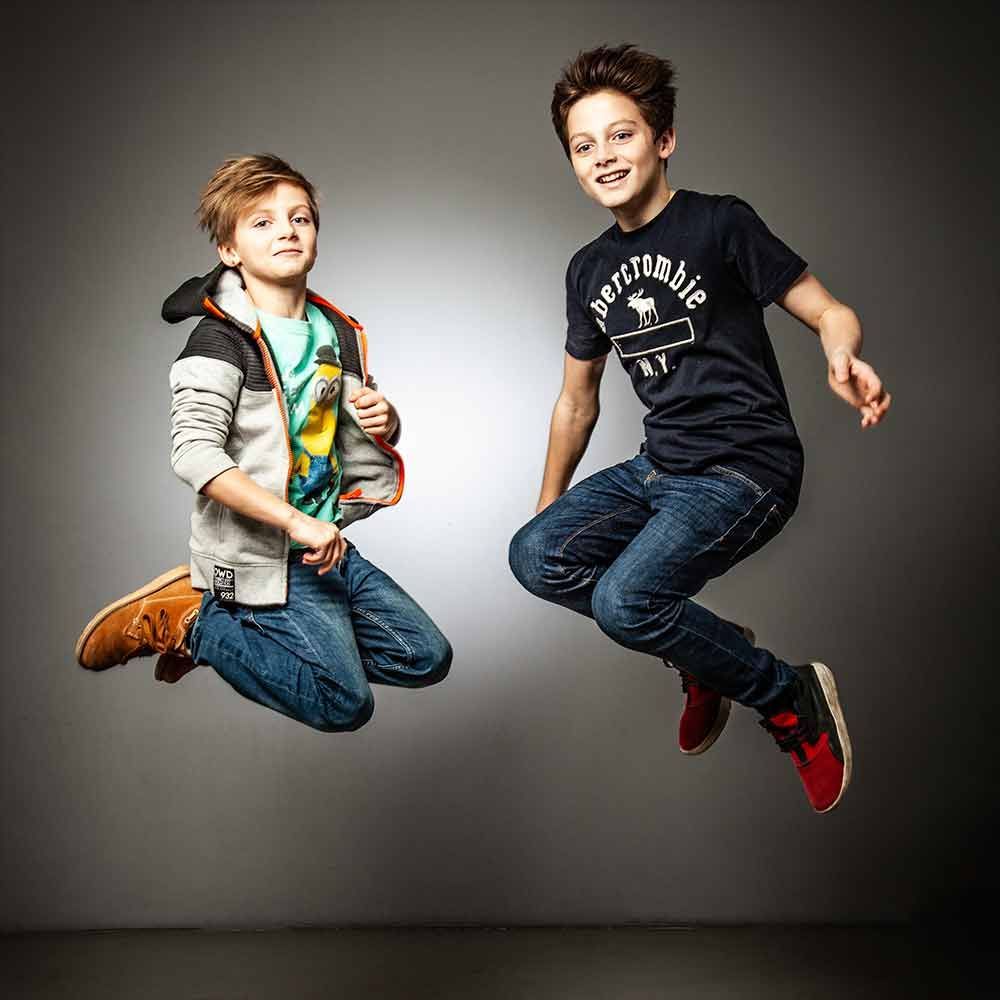 Zwei kleine Jungen springen gemeinsam in die Luft.