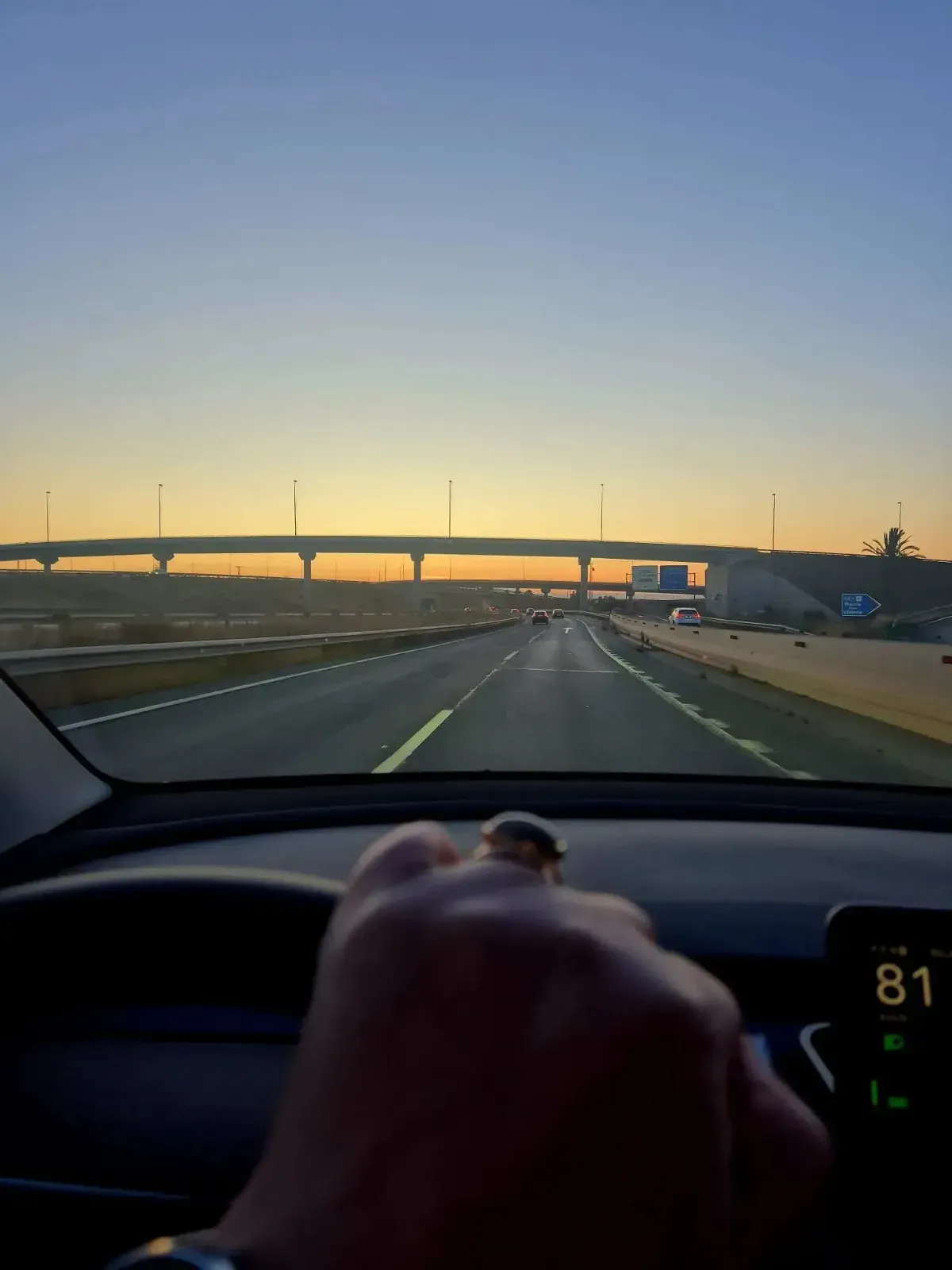 Una persona vestida de traje se encuentra junto a un Tesla negro en una calle de la ciudad.