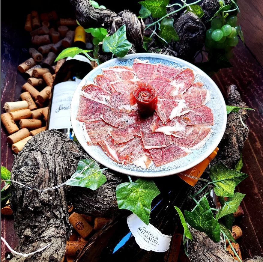 Un plato de carne está rodeado de corchos de vino y hojas.