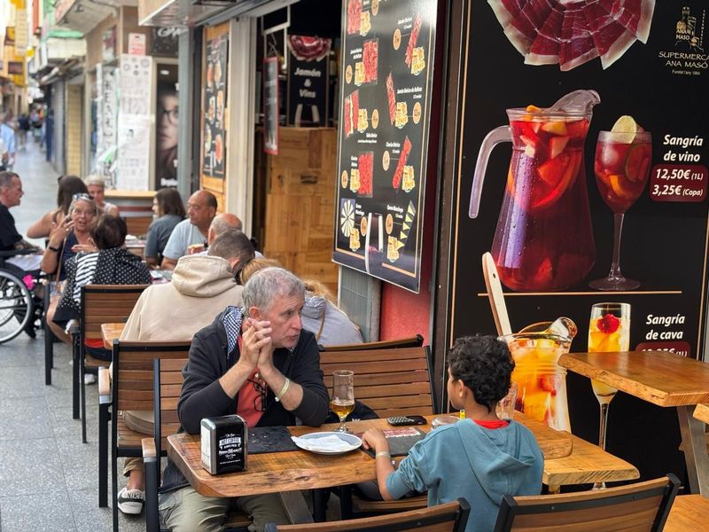 Un grupo de personas están sentadas en mesas afuera de un restaurante.