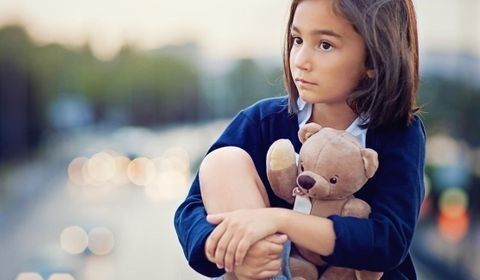 Une enfant tient un ours en peluche dans ses bras