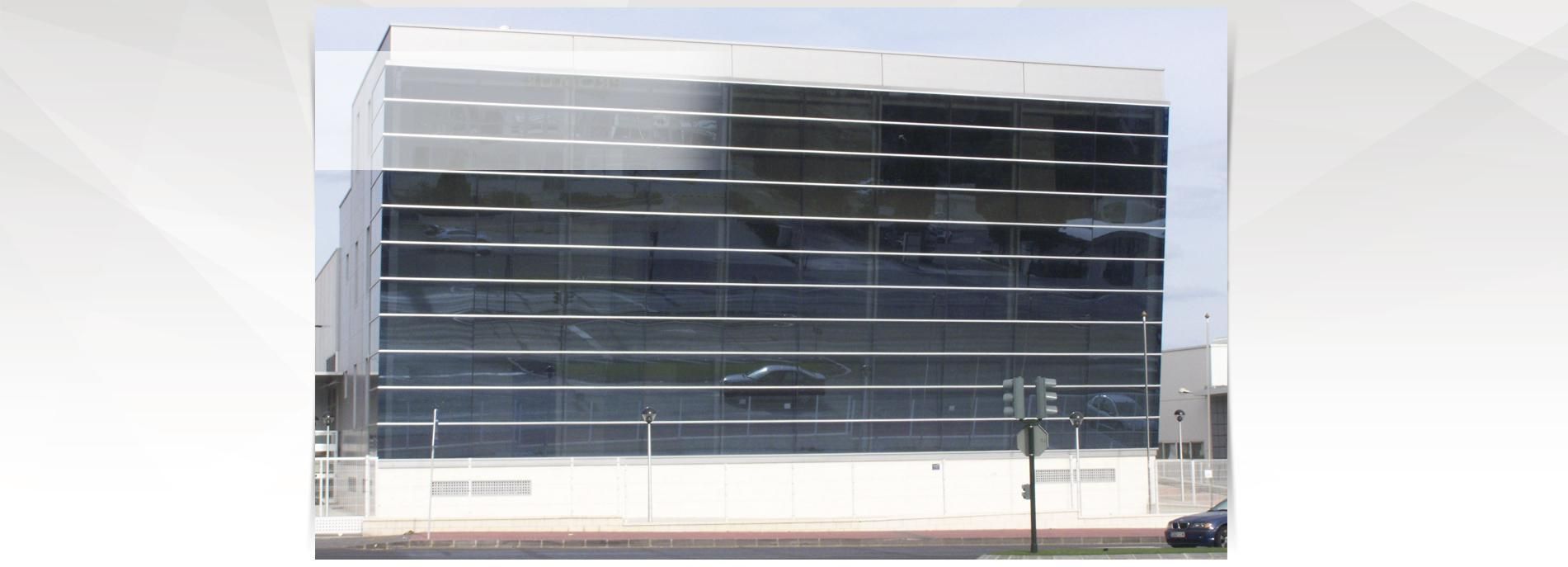 Un edificio grande con muchas ventanas y un coche aparcado delante.