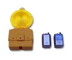 Luz de peligro amarilla en la carretera y dos baterías de 9 voltios sobre una superficie blanca.