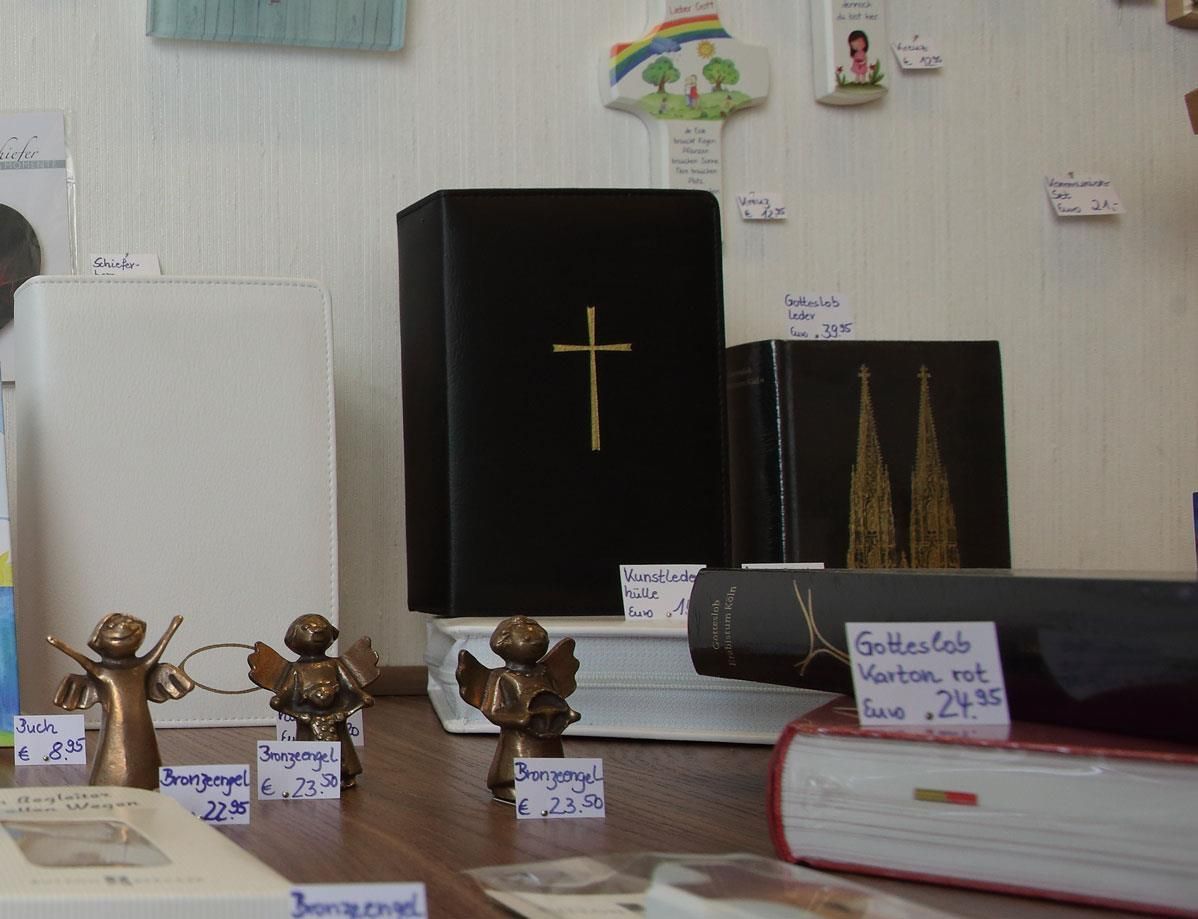 Ein schwarzes Buch mit einem goldenen Kreuz darauf liegt auf einem Tisch