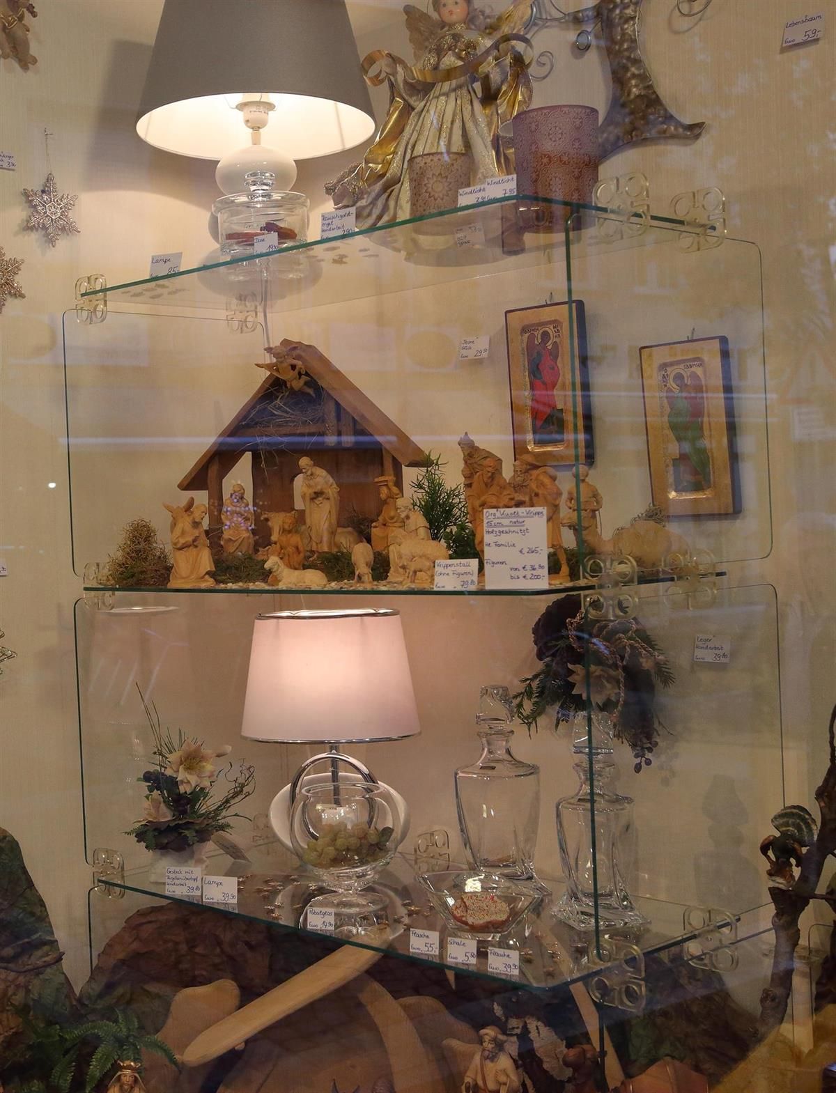 Ein Glasregal mit einer Lampe und einer Weihnachtskrippe darauf