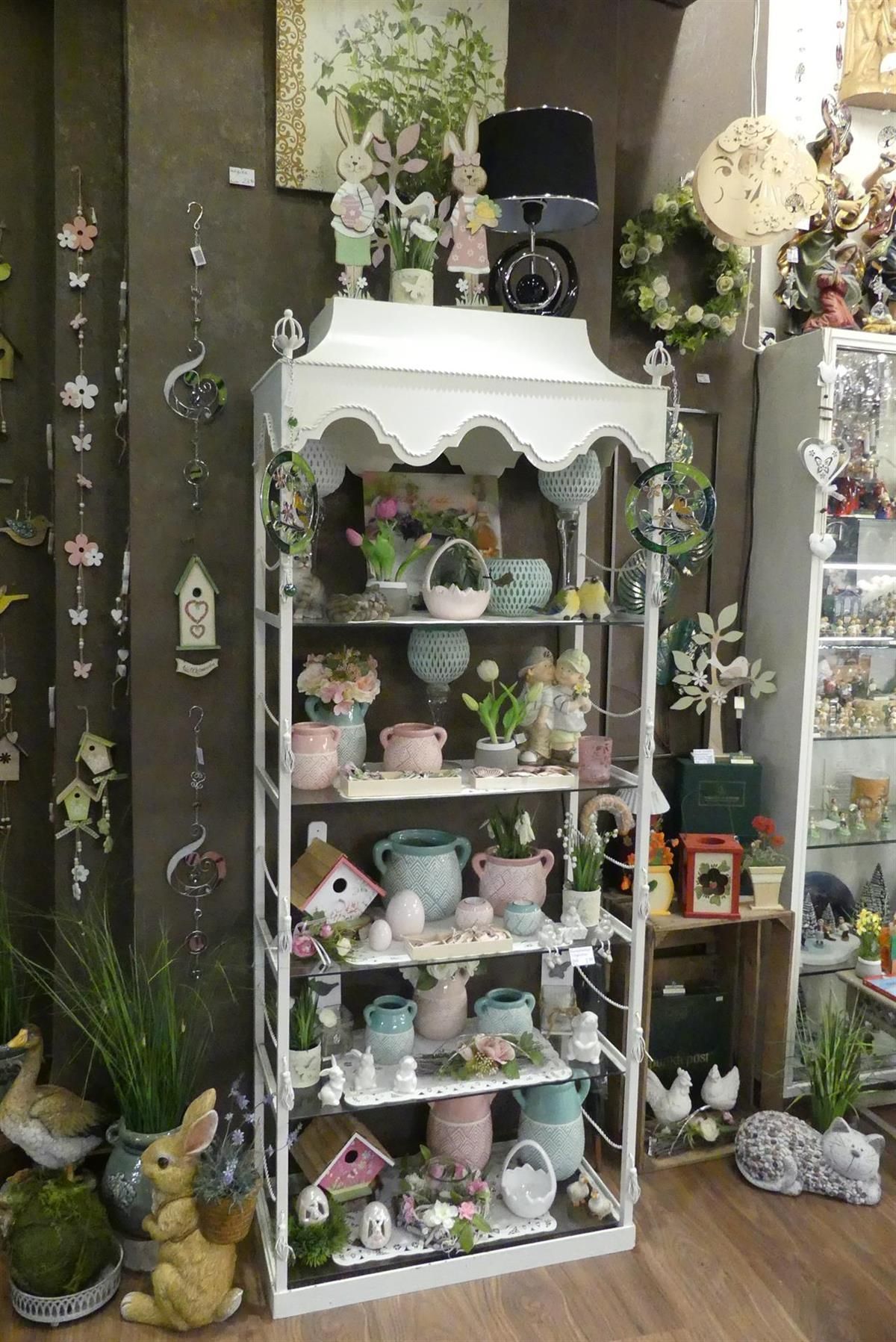 Ein Regal mit vielen Topfpflanzen und Figuren