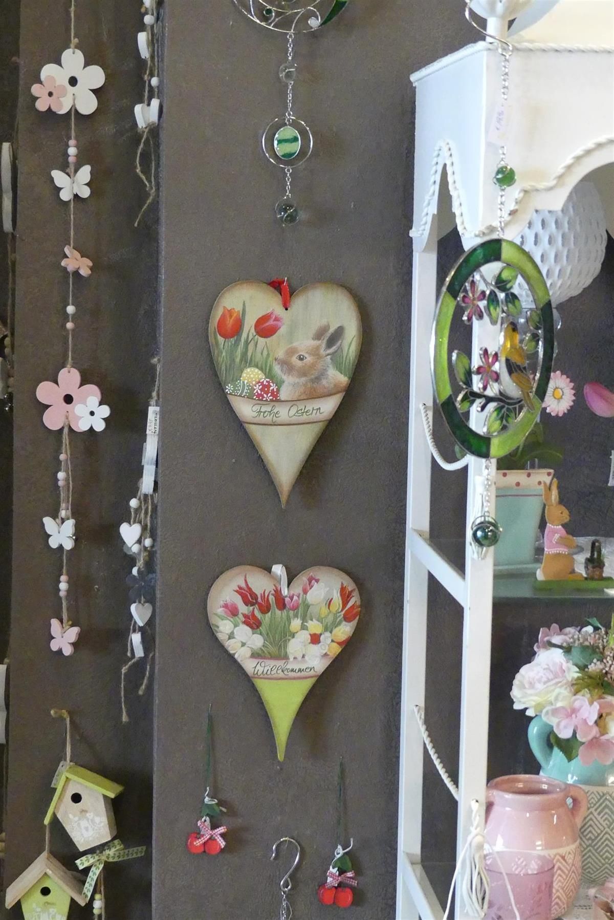 Drei Herzen mit Blumen darauf hängen an einer Wand