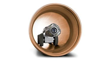 Una cámara está dentro de una tubería sobre un fondo blanco.