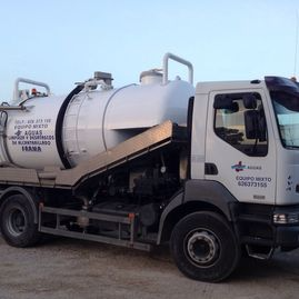 Un camión de vacío blanco está estacionado en un camino de tierra