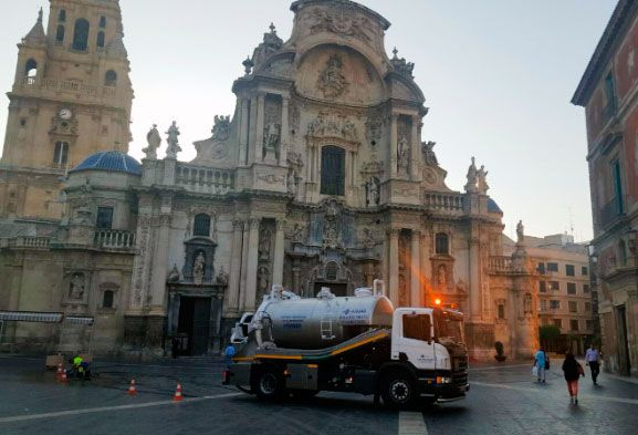 Un camión de vacío está estacionado frente a un gran edificio.