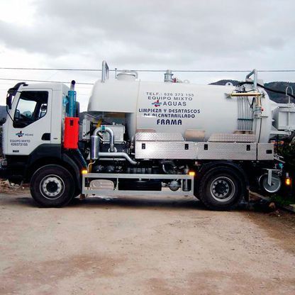 Un camión blanco y negro está estacionado en un lote de tierra.