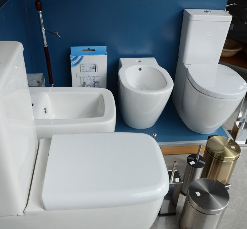 Un baño con inodoros blancos y bidé.