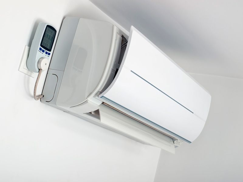 Un acondicionador de aire blanco con un control remoto adjunto.