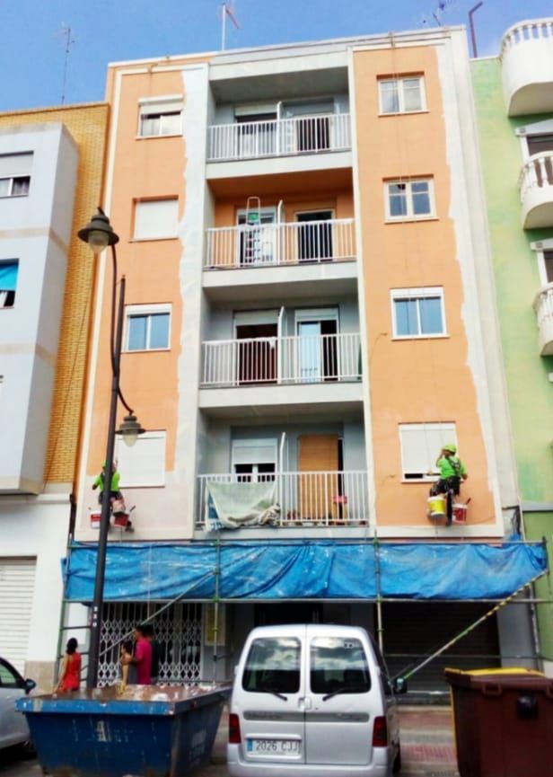 Una camioneta está estacionada frente a un edificio que se está pintando