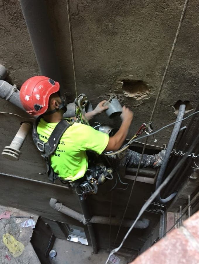 Un hombre que lleva un casco y una camisa verde neón está trabajando en una pared.