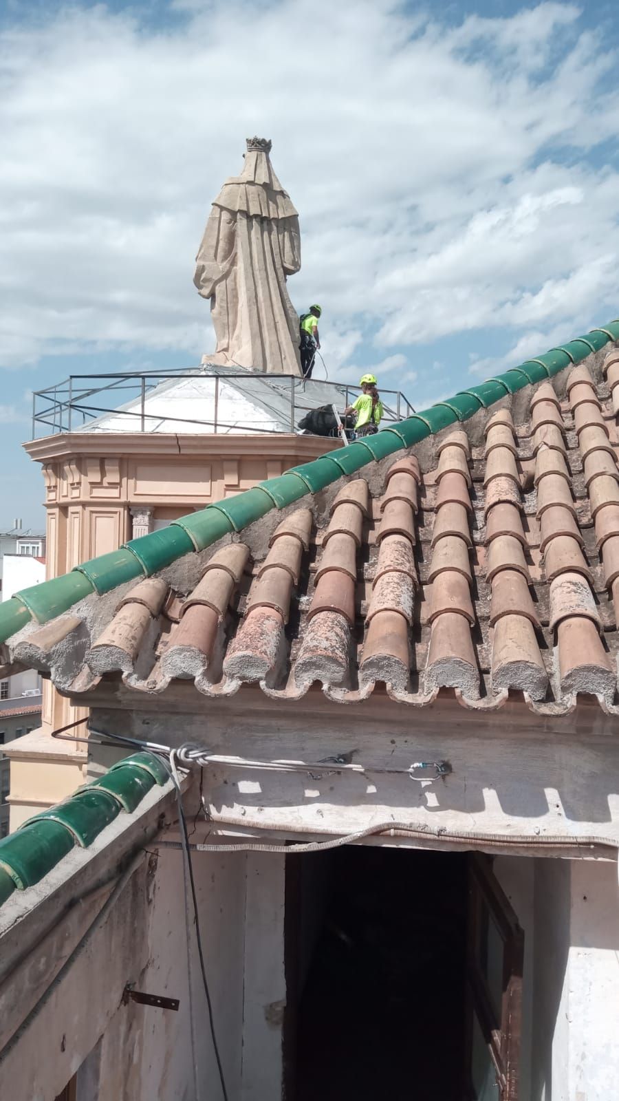 Una estatua de un hombre está sentada en lo alto de un tejado.