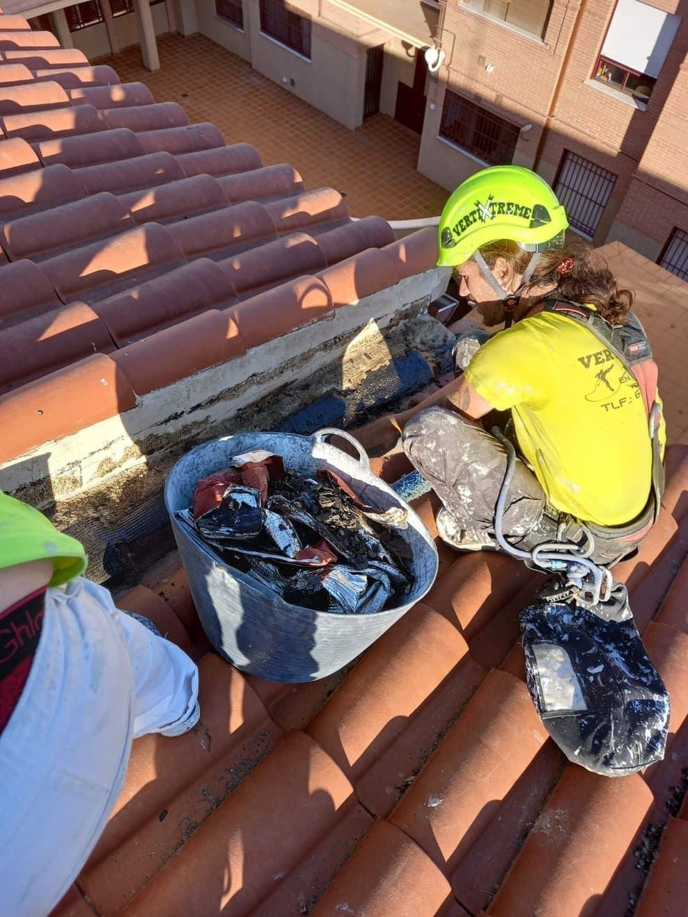 Dos hombres están sentados encima de un tejado de tejas.