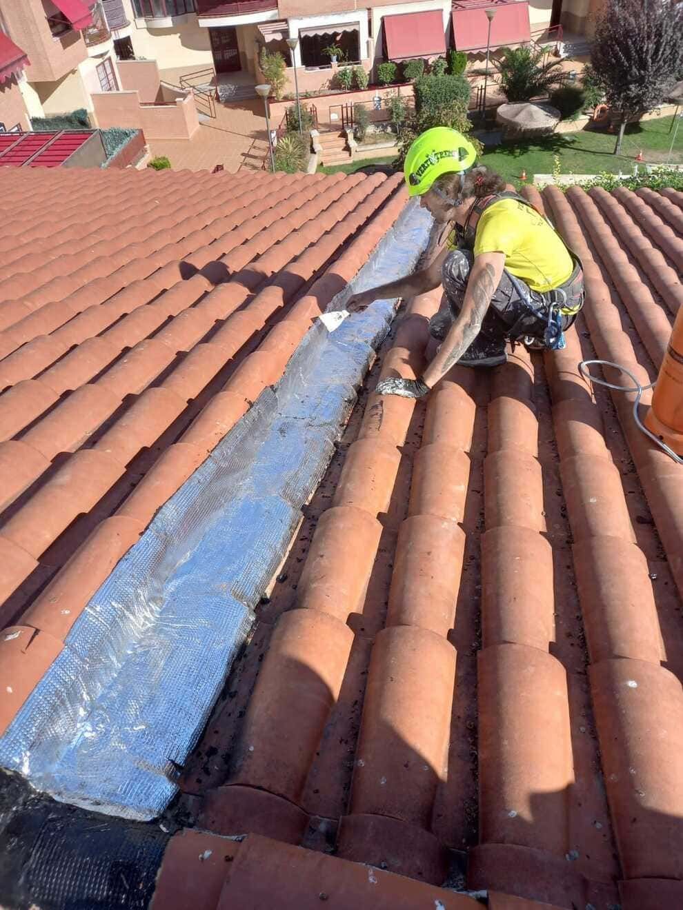 Un hombre está trabajando en el techo de una casa.