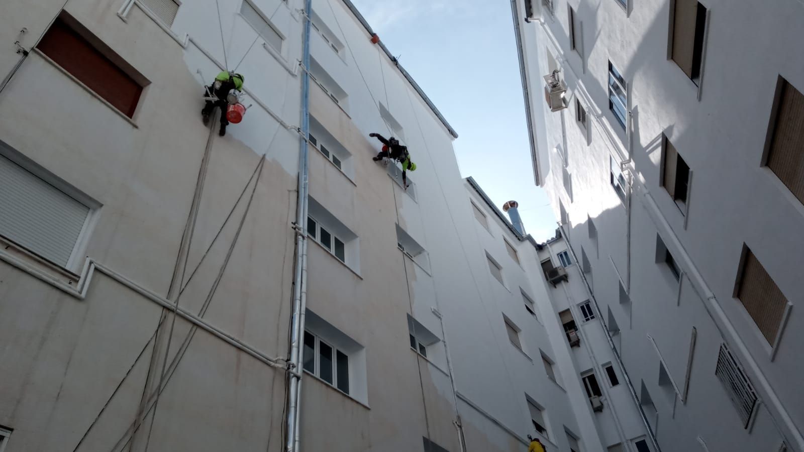 Dos hombres están subiendo por el costado de un edificio.