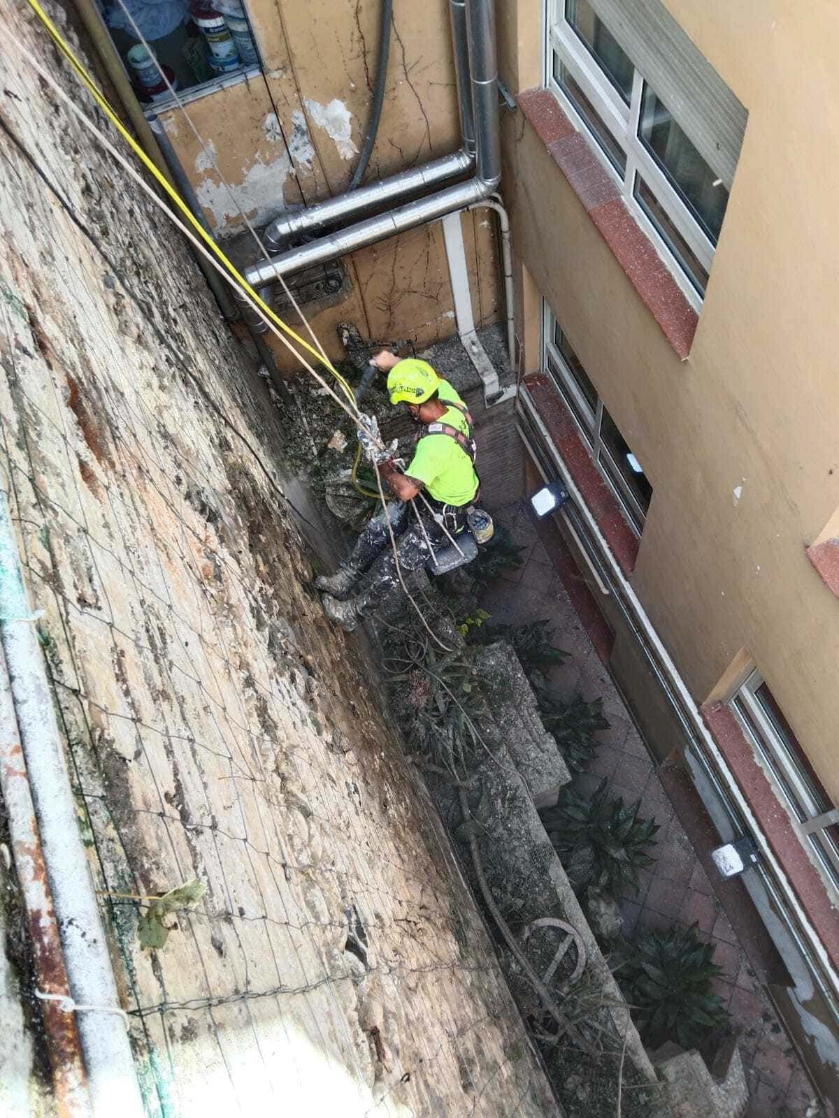 Un grupo de personas está trabajando en el lateral de un edificio.