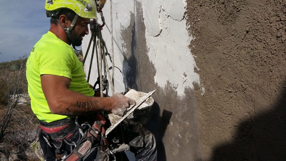Un hombre está trabajando en una pared con una paleta.
