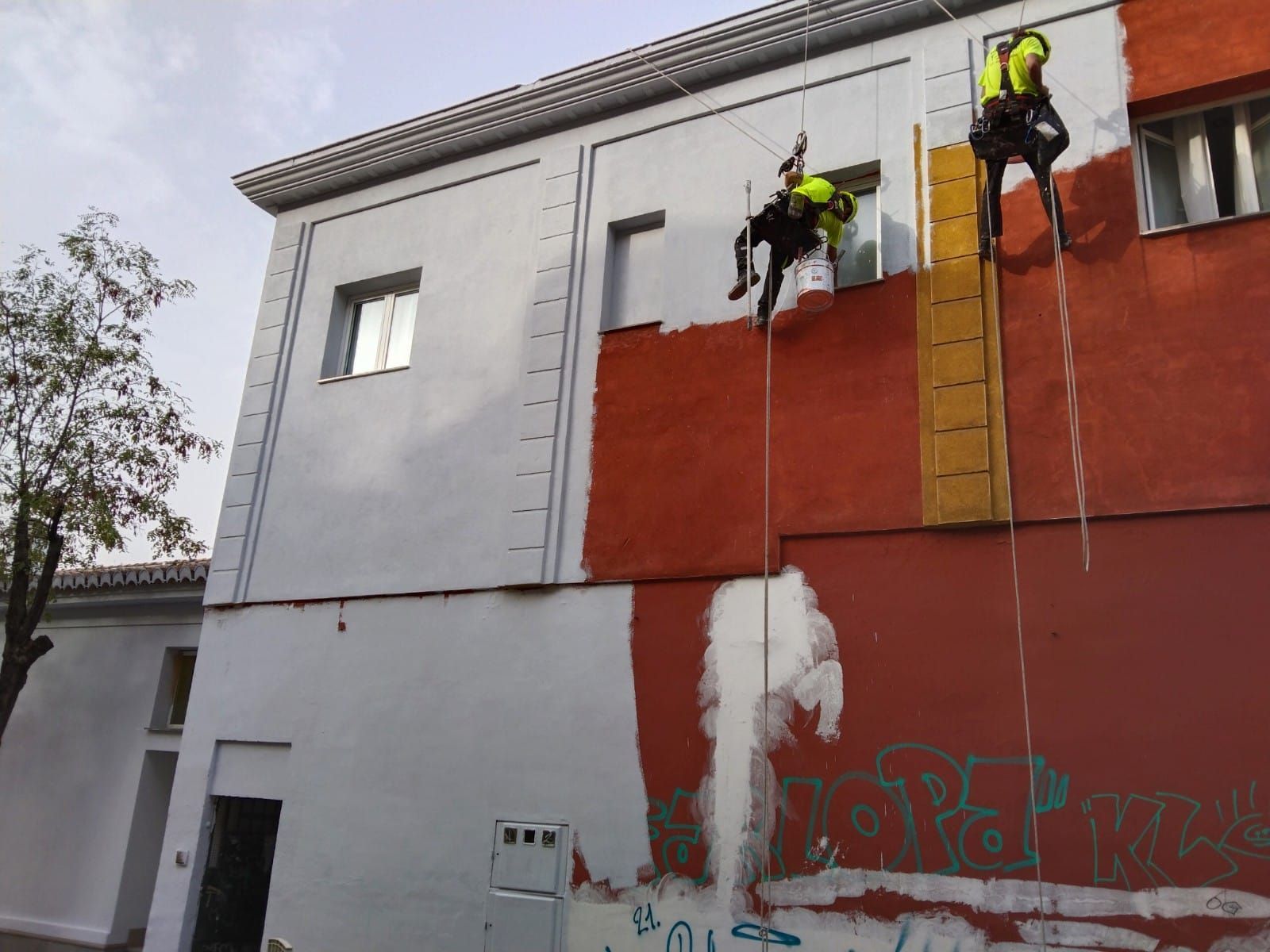 Dos hombres están subiendo por el costado de un edificio.