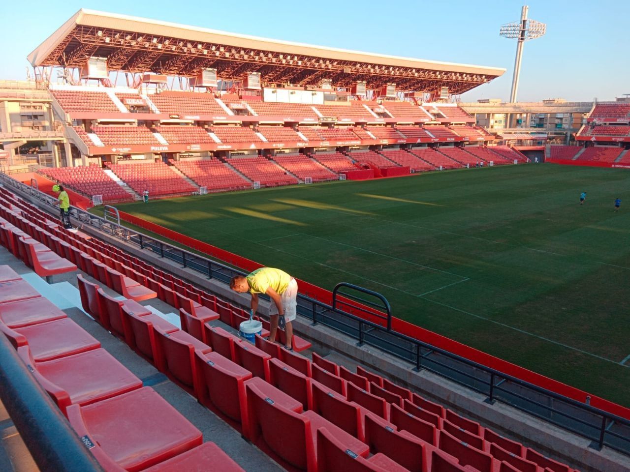 Un hombre está limpiando los asientos de un estadio.