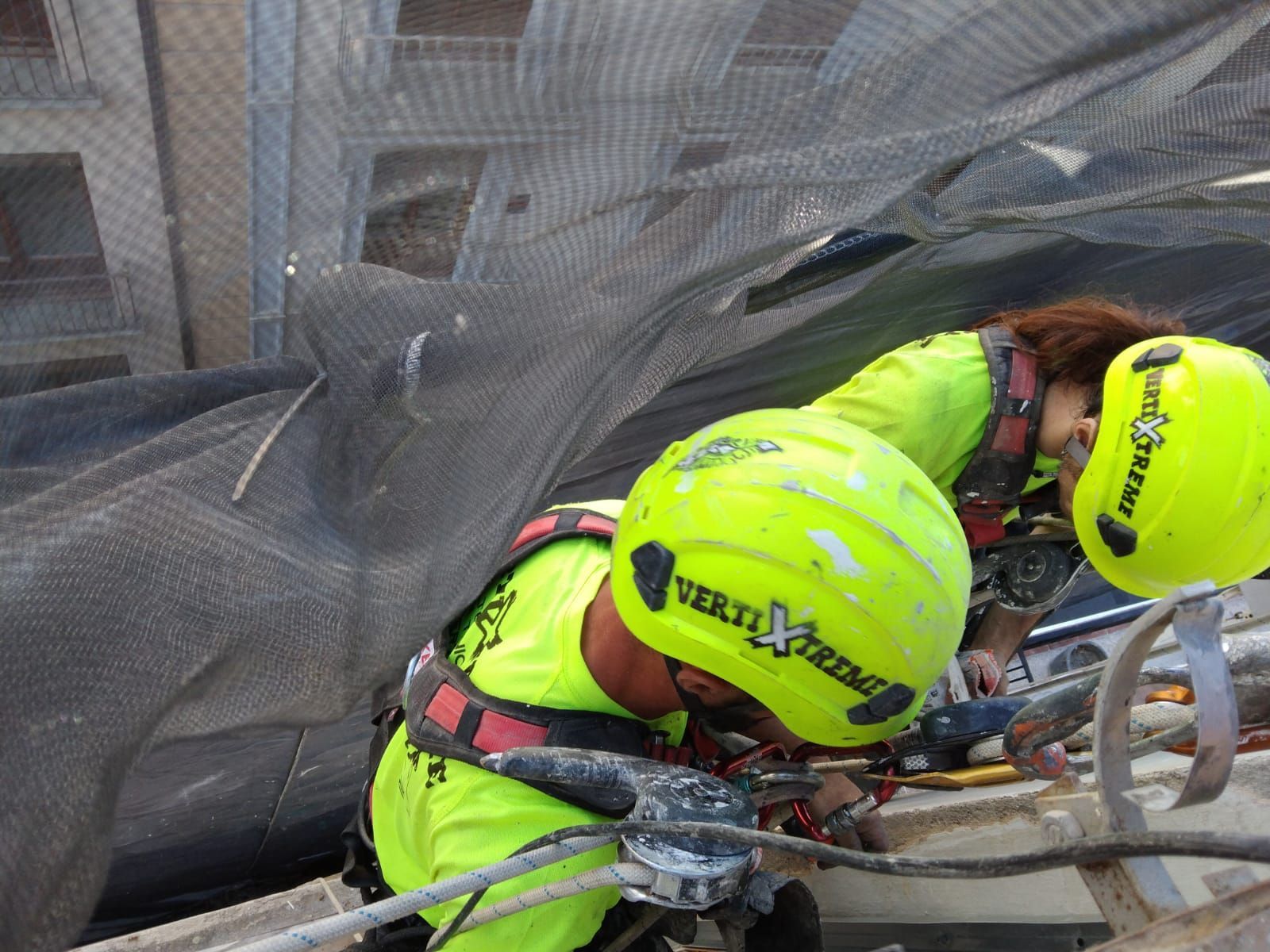 Un hombre y una mujer que llevan cascos amarillos están trabajando en un edificio.