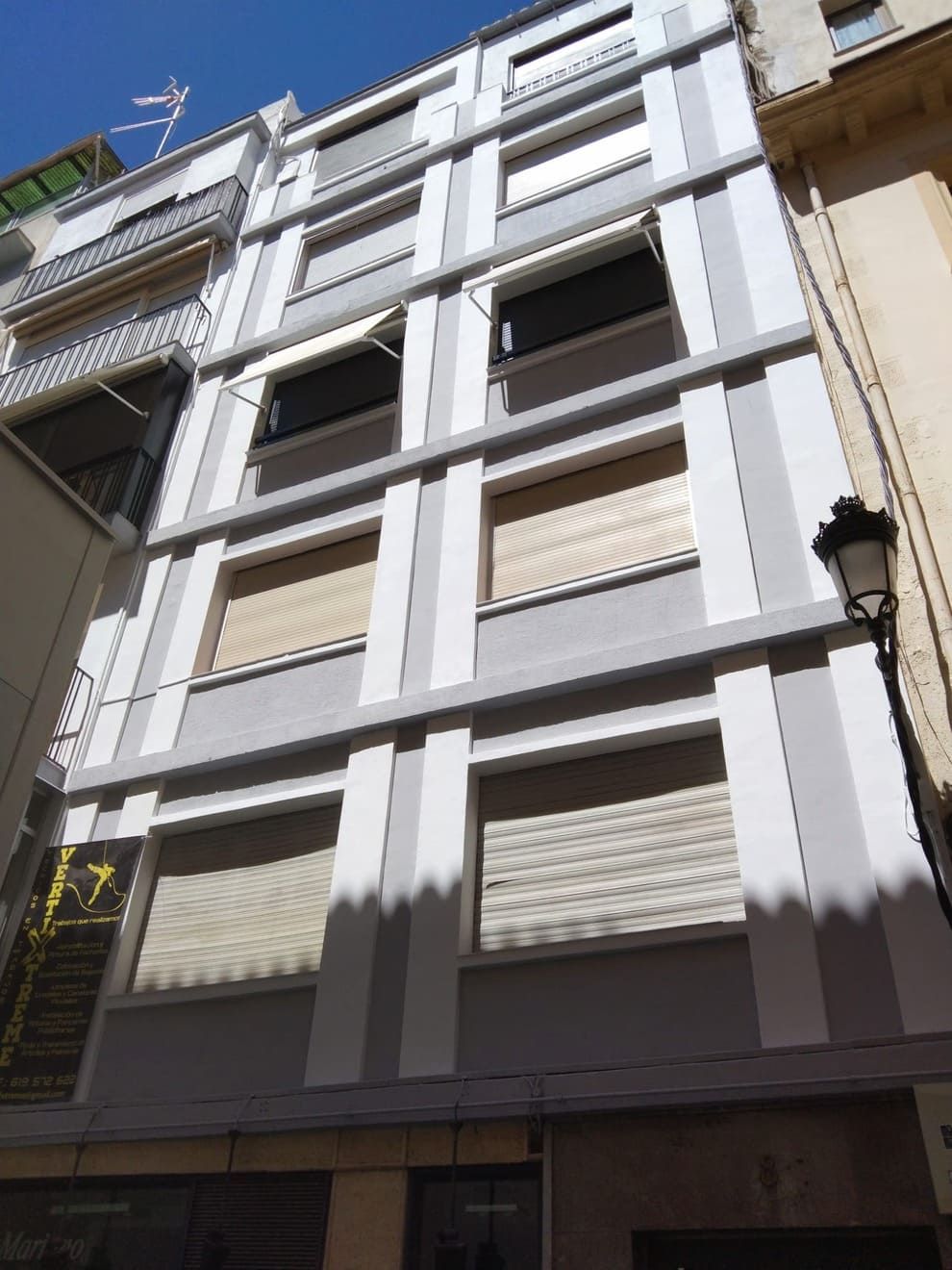 Un edificio alto con muchas ventanas y una farola delante.