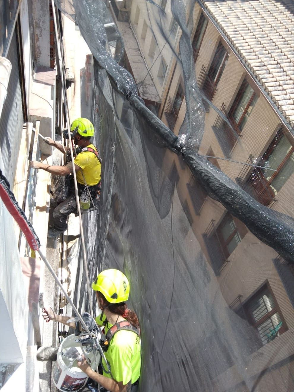 Un grupo de personas está trabajando en el lateral de un edificio.