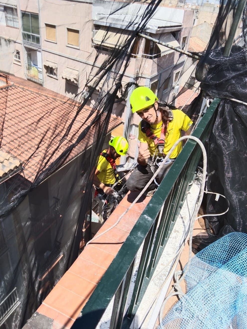 Un grupo de personas con cascos amarillos están trabajando en un balcón.