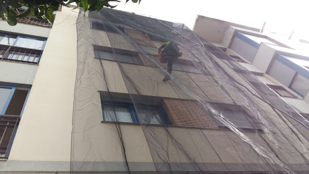 Un hombre está subiendo por el costado de un edificio.