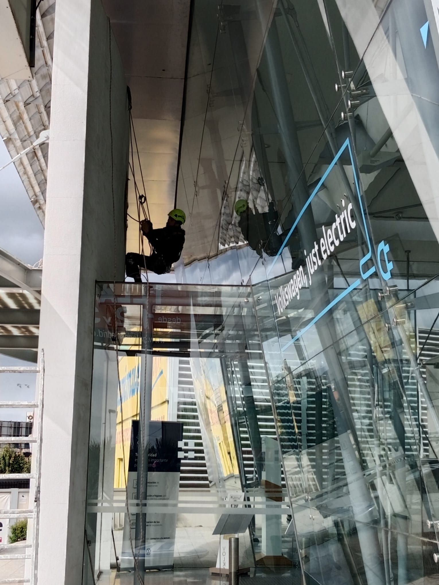 Un hombre está limpiando un edificio de cristal con cuerdas.