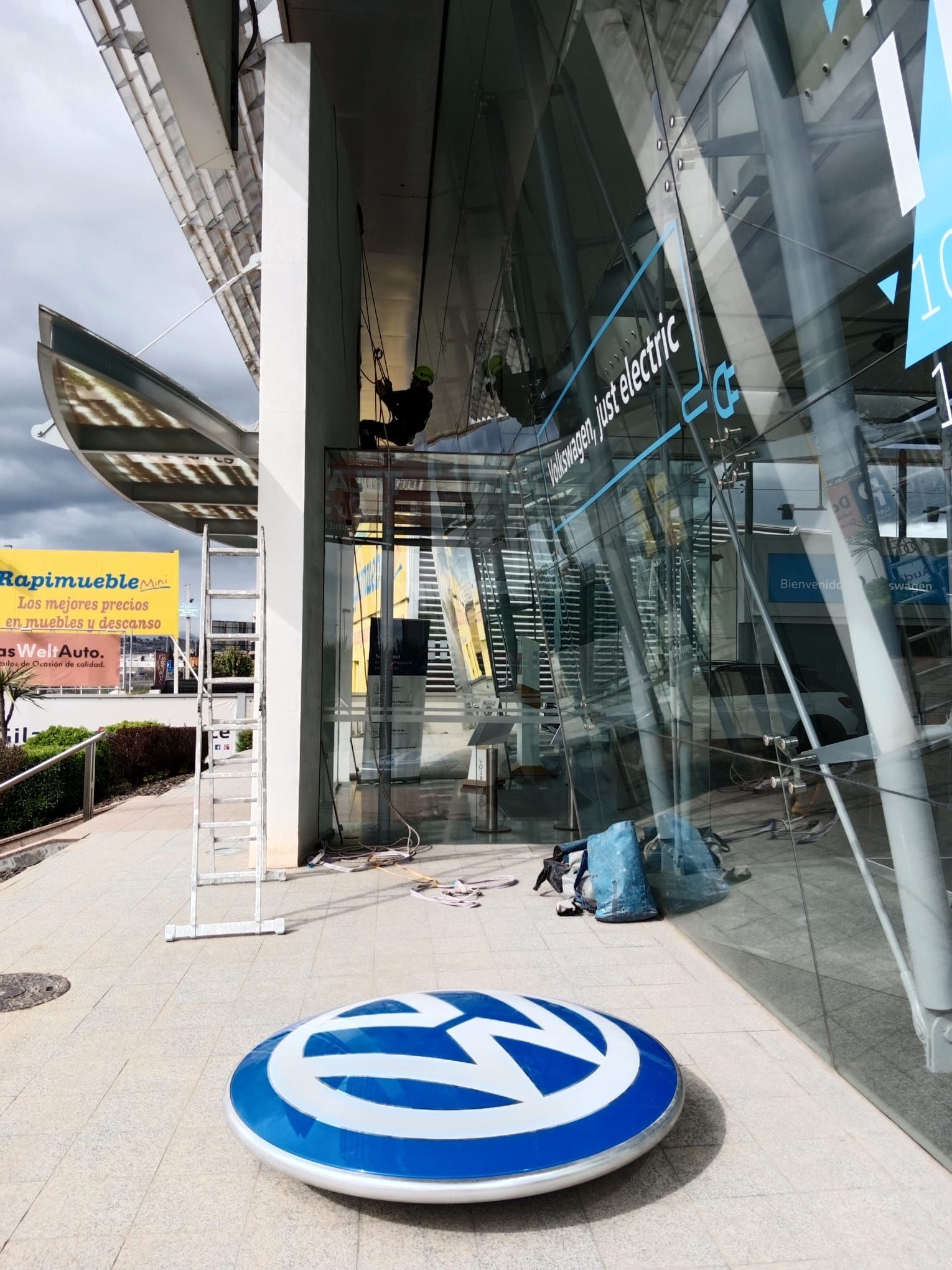 Un logotipo de Volkswagen azul y blanco está en el suelo frente a un edificio.