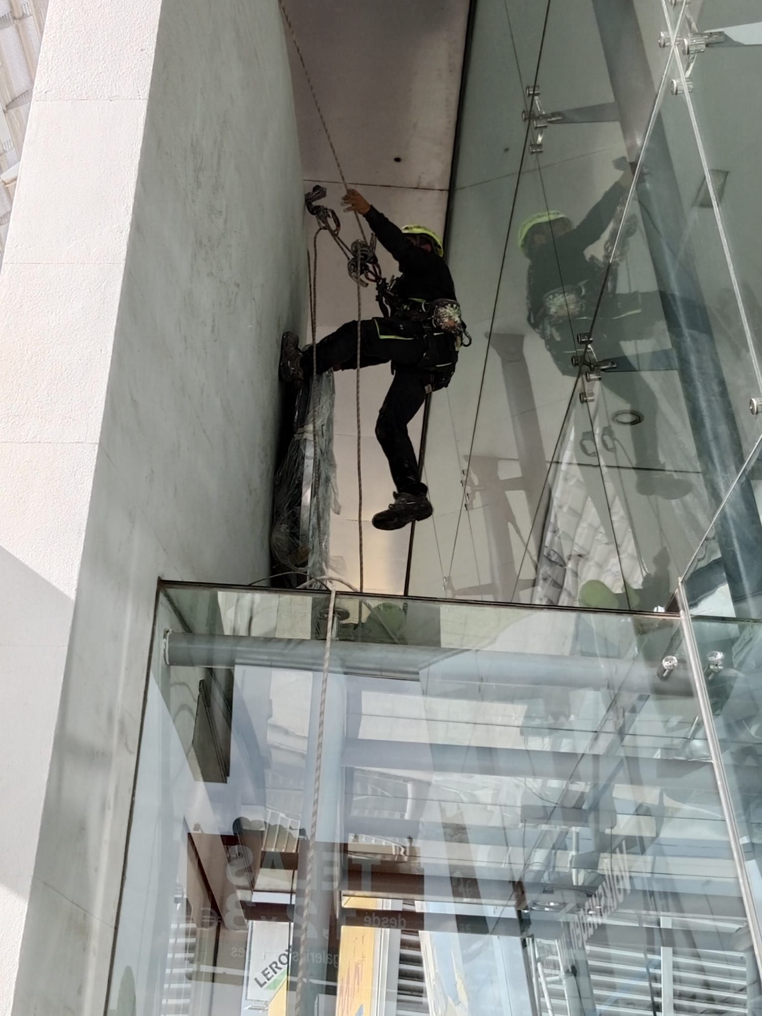 Un hombre está trepando por una pared de cristal.