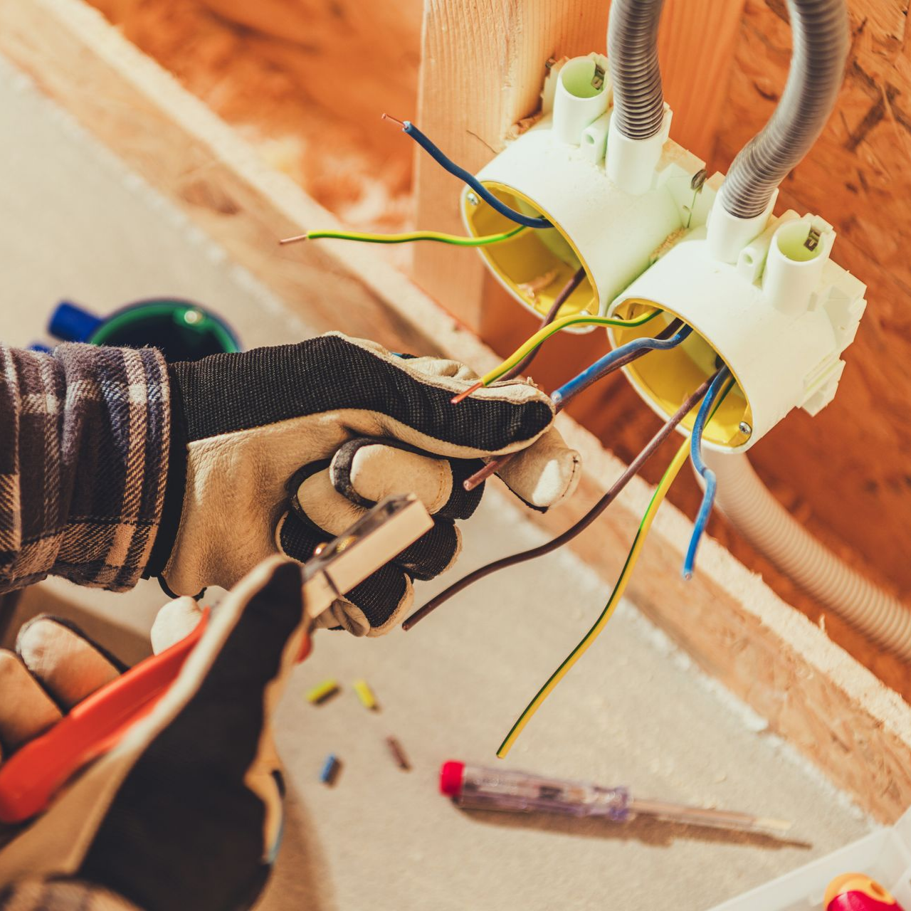 Un électricien intervenant sur une prise électrique.
