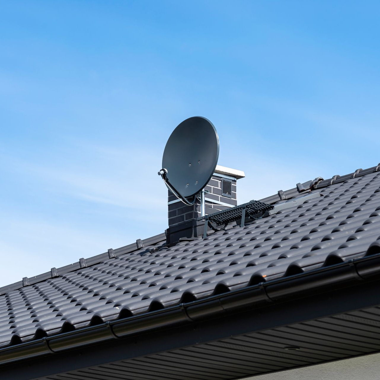 Antenne parabolique devant un ciel bleu.