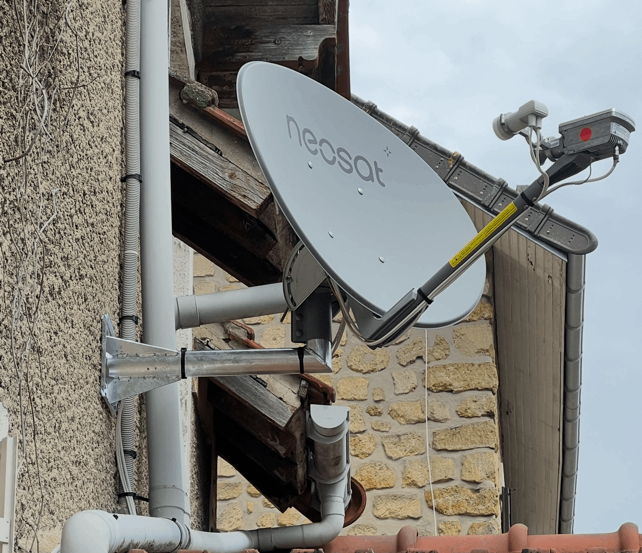 Une antenne parabolique blanche fixée à l'extérieur d'un bâtiment.
