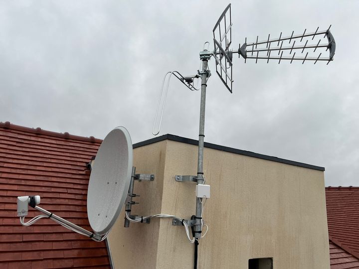 Une antenne parabolique blanche fixée à l'extérieur d'un bâtiment.