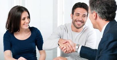 Un hombre y una mujer se dan la mano con un hombre de traje.