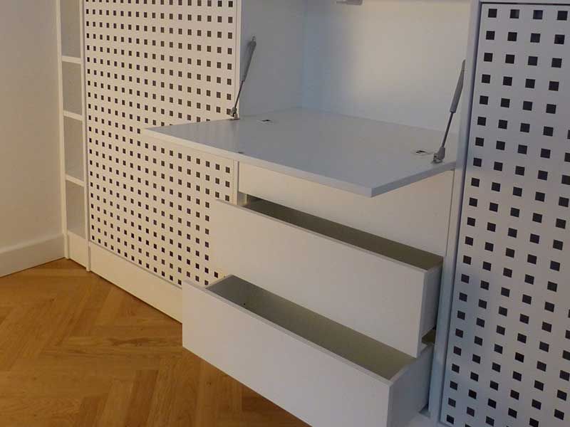 Eine weiße Kommode mit drei Schubladen und einem Regal