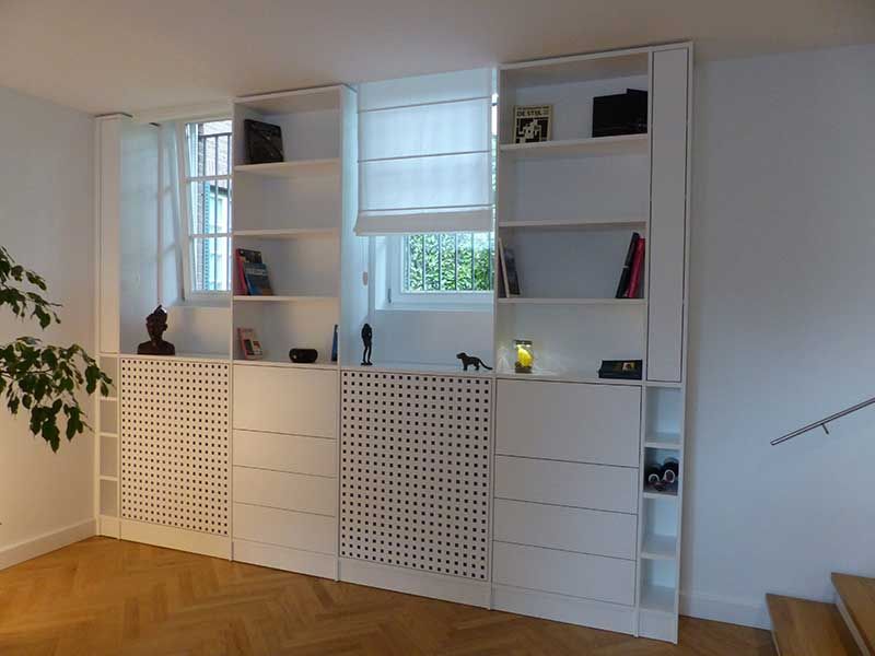 Ein Wohnzimmer mit vielen weißen Regalen und Schubladen