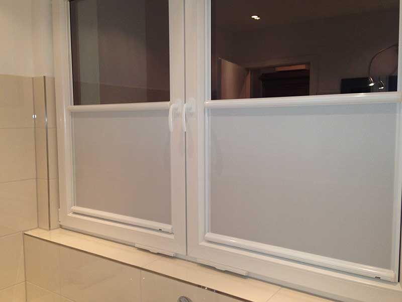 Ein Badezimmer mit zwei Fenstern mit Jalousien.