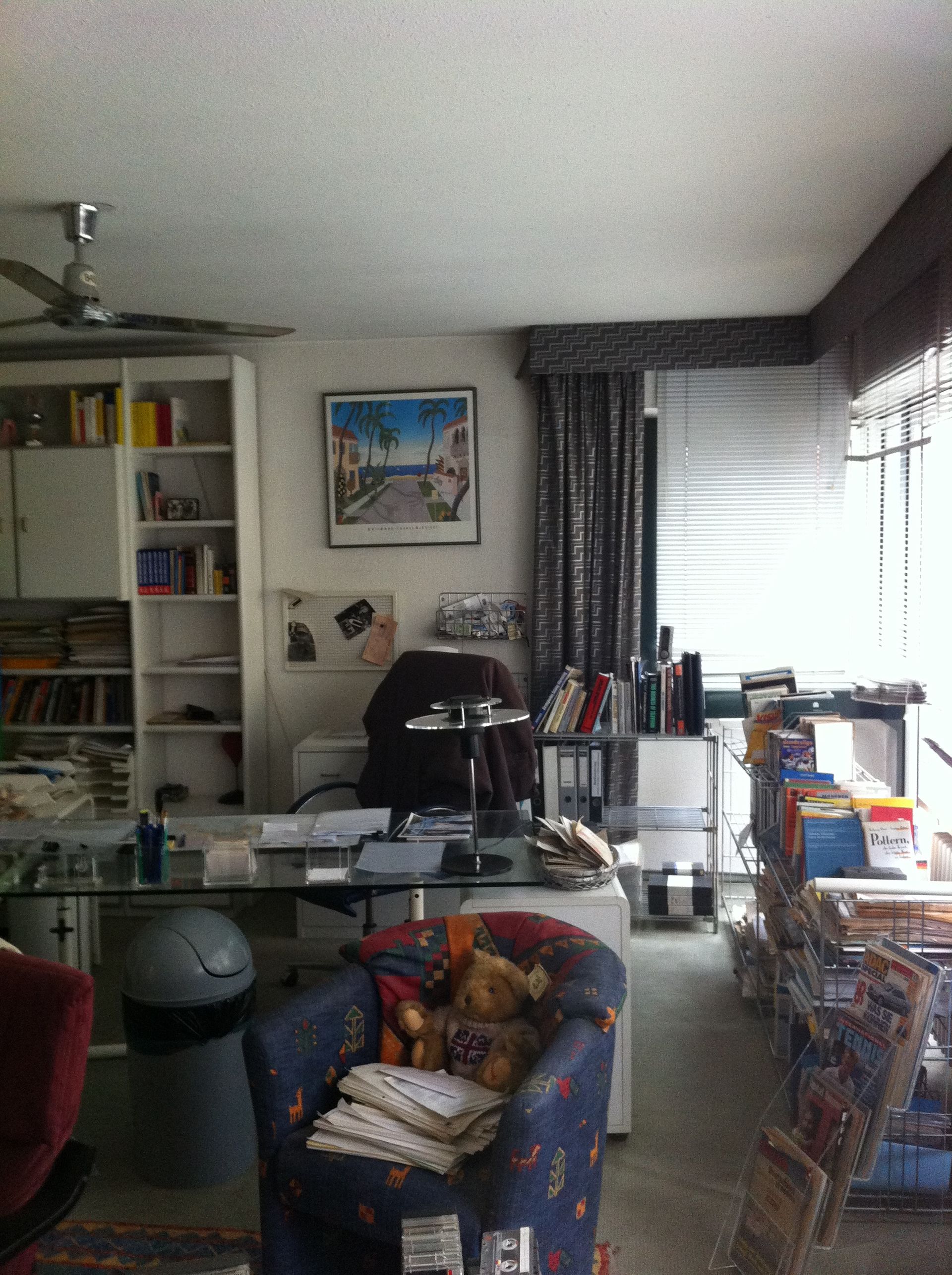 Ein Wohnzimmer mit einem Stuhl und einem Schreibtisch mit einem Bild an der Wand darüber