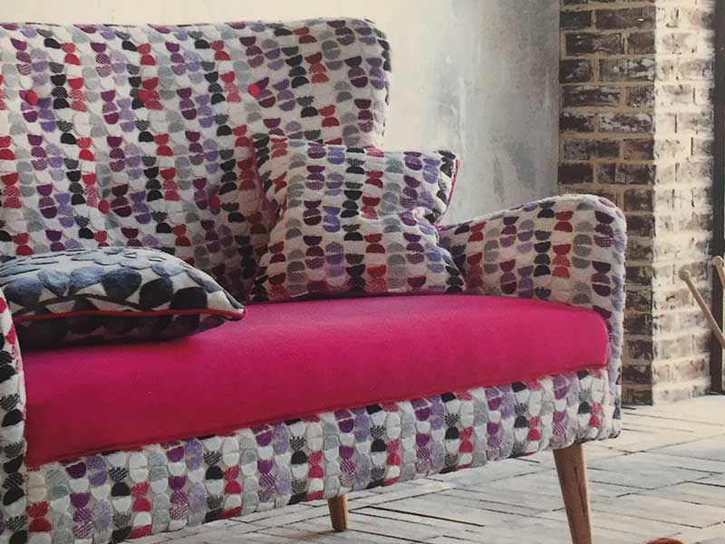 Eine bunte Couch mit rosa Polstern und Kissen
