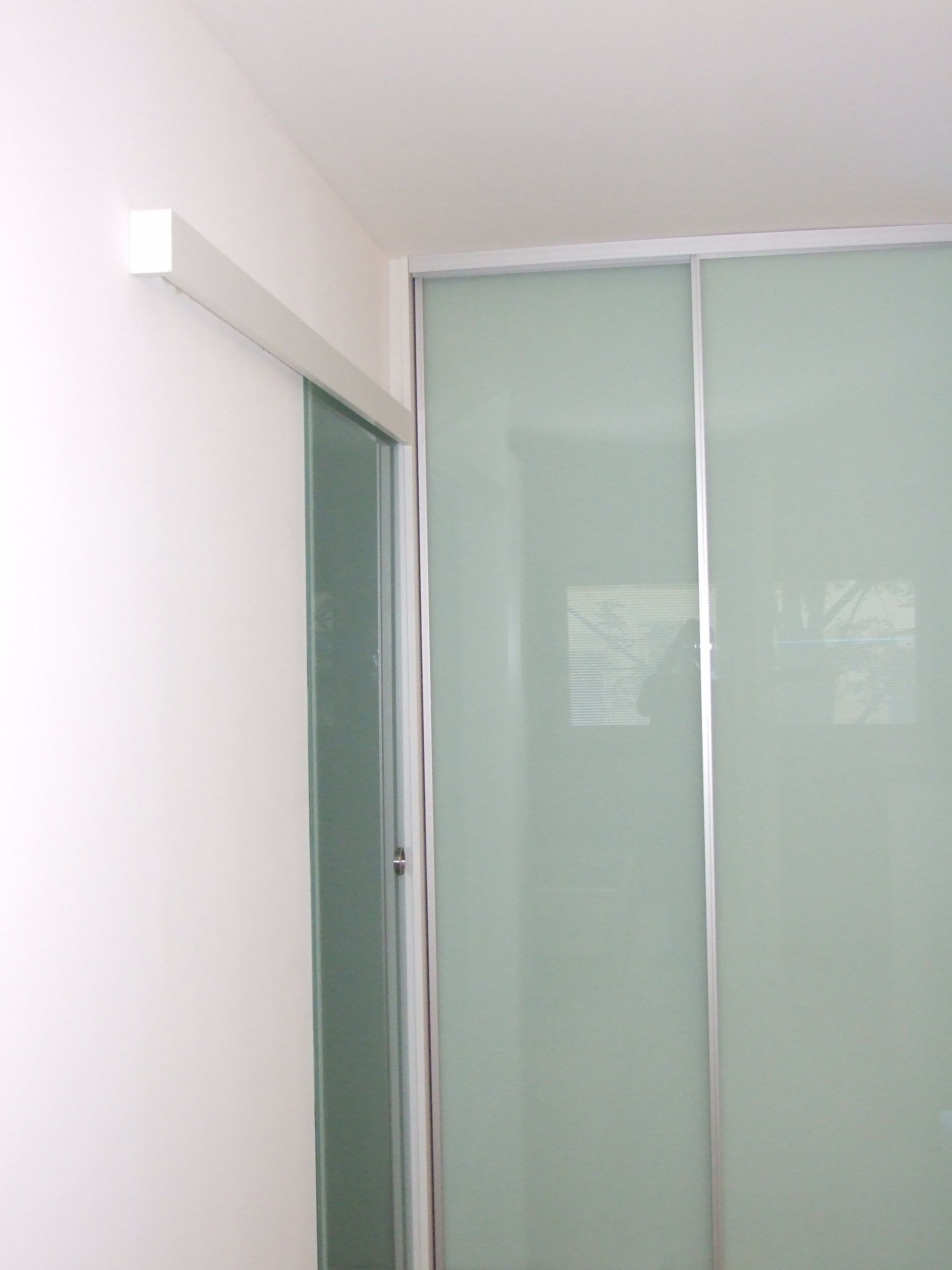 In der Ecke des Zimmers befindet sich eine Glasschiebetür.