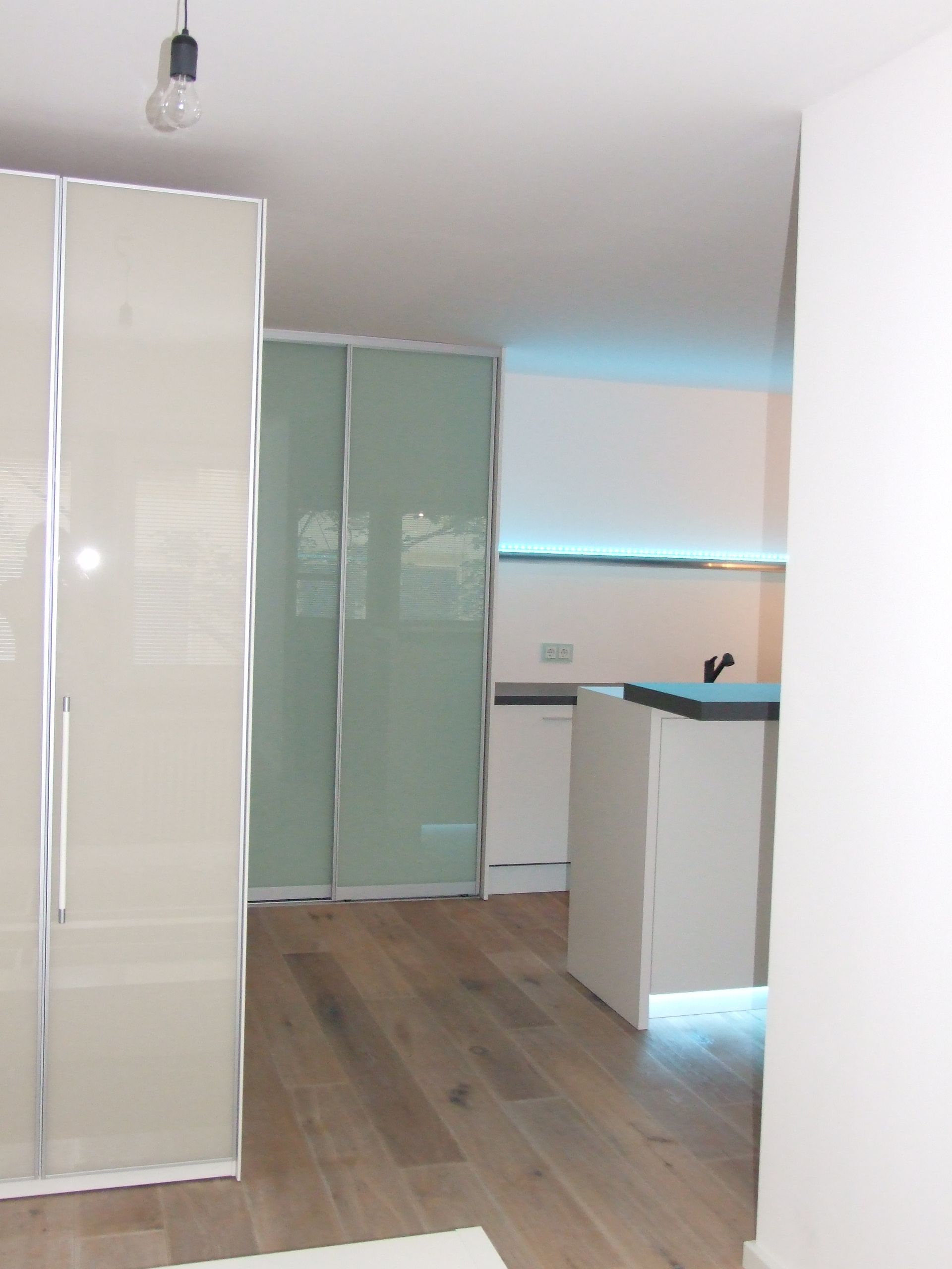 Eine Küche mit weißen Schränken und grünen Glastüren