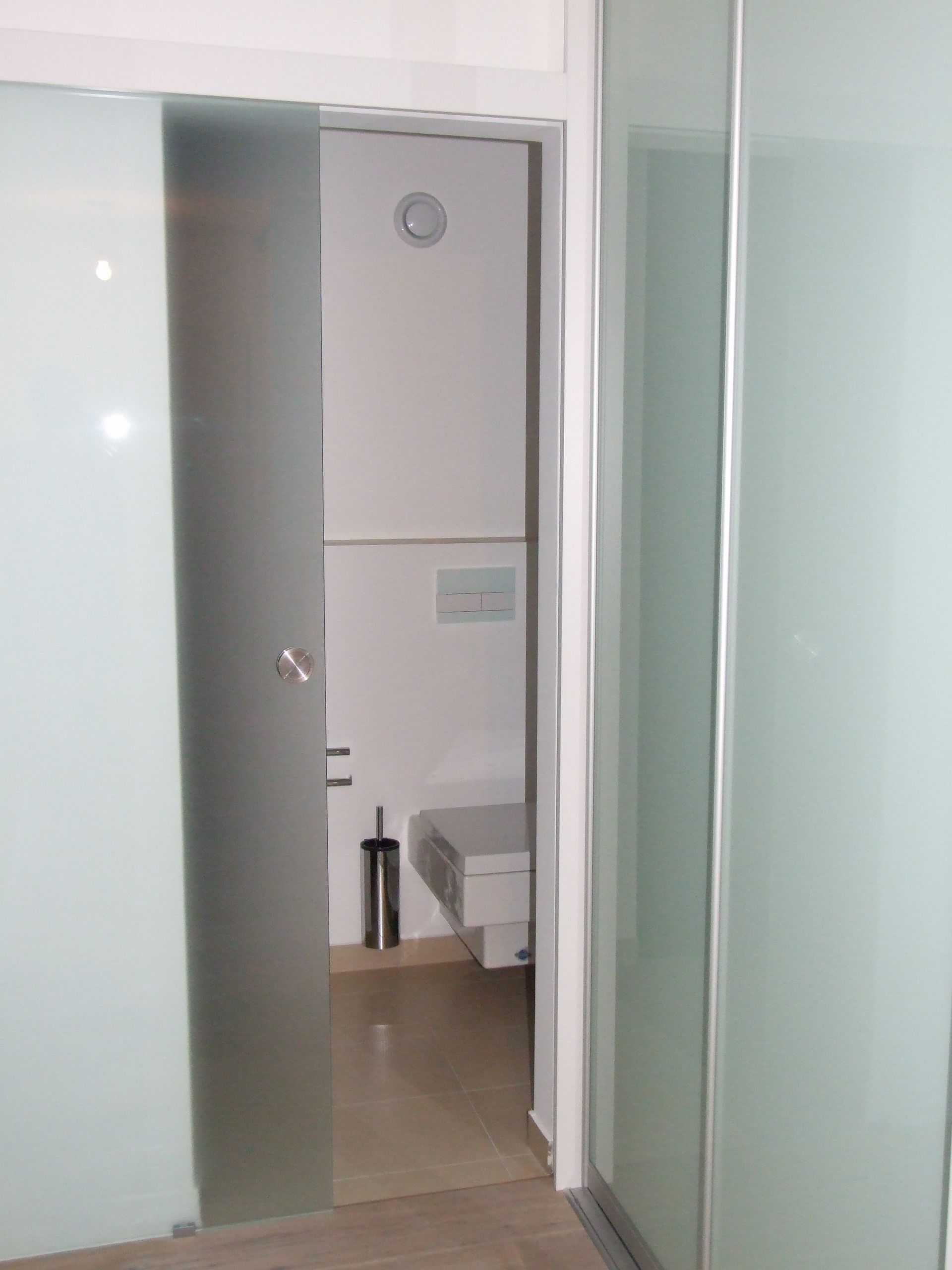 Ein Badezimmer mit Toilette und Glasschiebetür