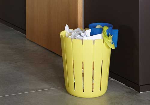 Eine gelbe Mülltonne steht neben einer Tür auf dem Boden.